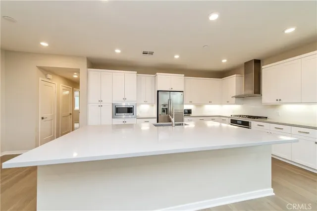 a kitchen with stainless steel appliances a sink a stove a refrigerator cabinets and a counter top space