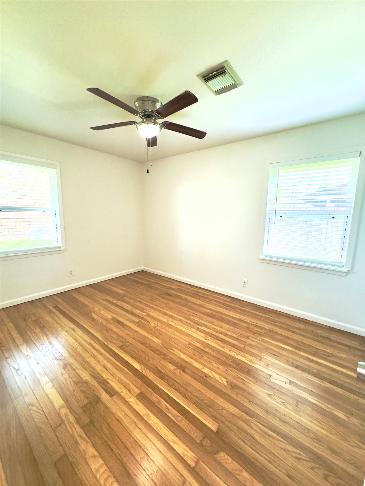 8733 Lugary Drive Houston, TX 77074 - Photo 16 of 30 an empty room with wooden floor ceiling fan and windows