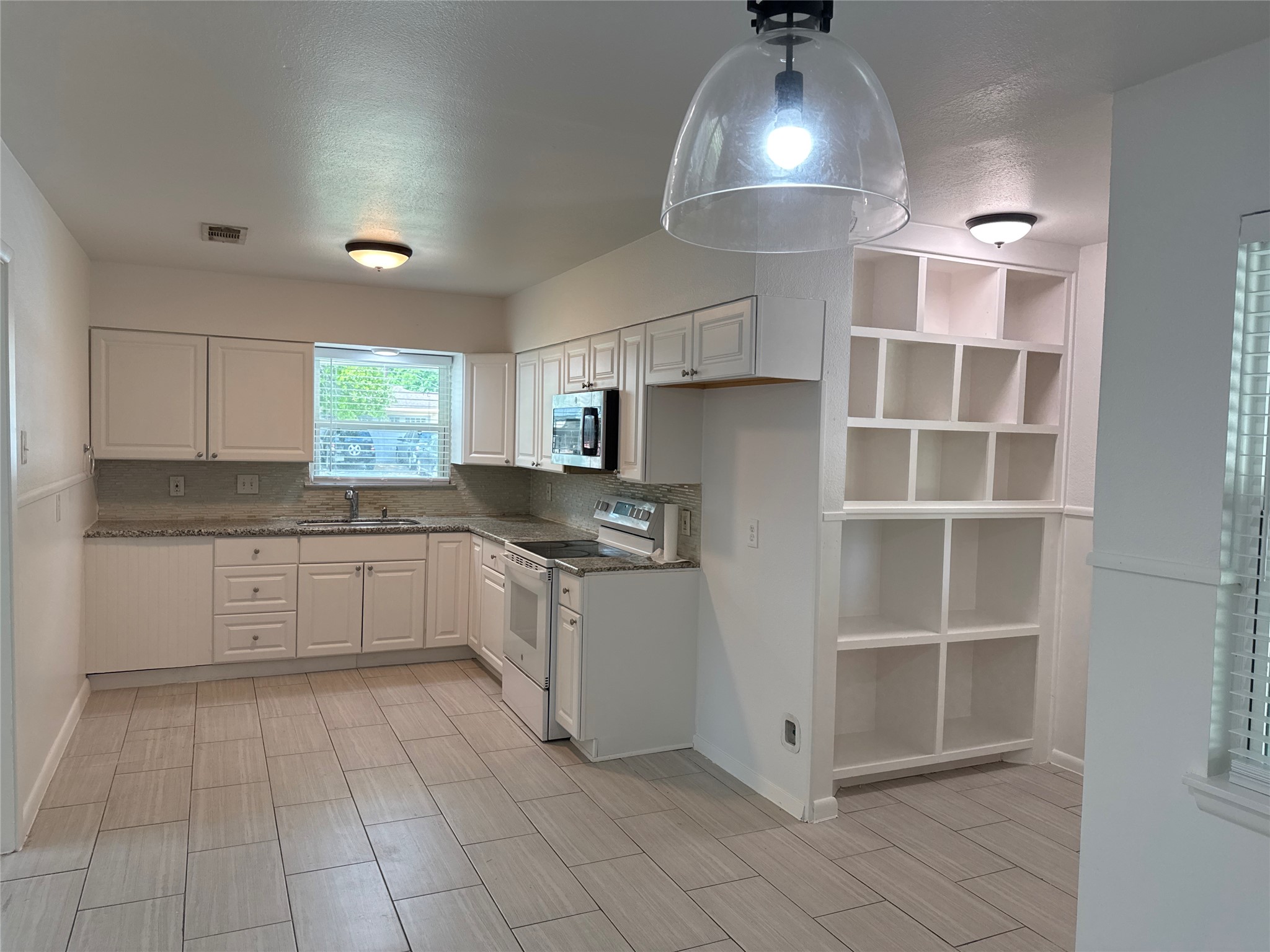 8733 Lugary Drive Houston, TX 77074 - Photo 4 of 30 a kitchen with granite countertop white cabinets stainless steel appliances a sink and a counter top space