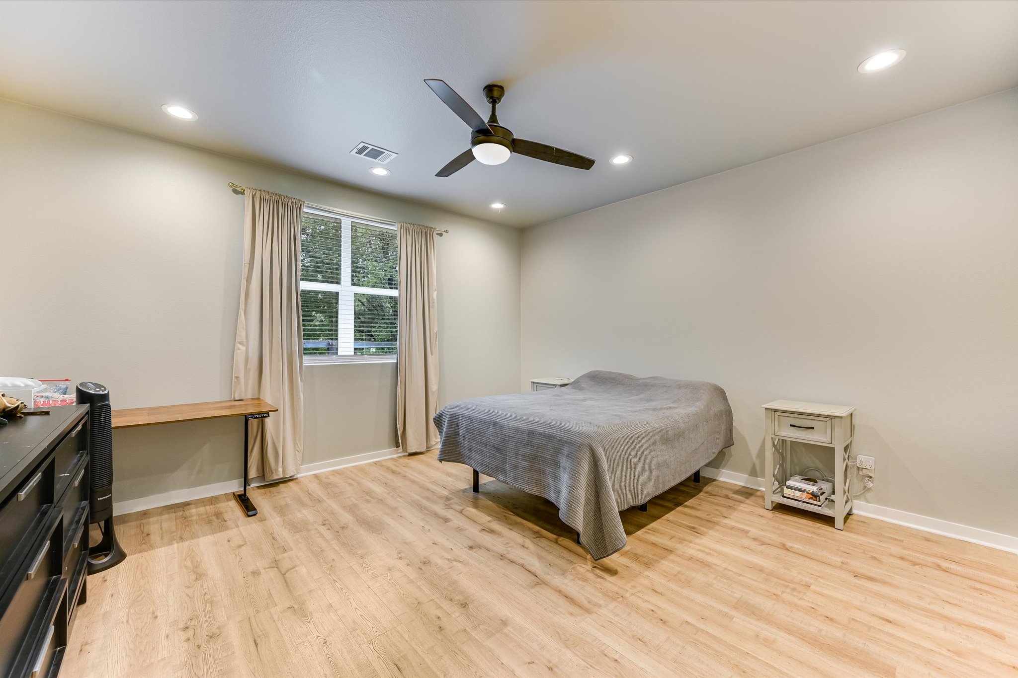 2308 Kellie Brooke Road, Unit 13 Spicewood, TX 78669 - Photo 11 of 19 A spacious room featuring light-toned walls, recessed lighting, a window with blinds and drapes, and light wood-style flooring