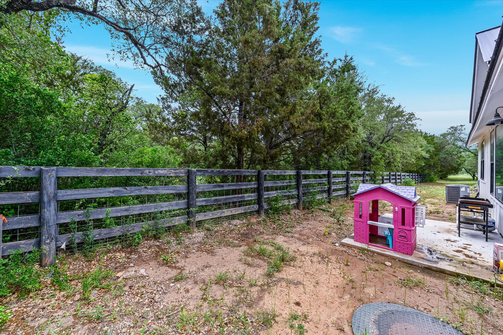2308 Kellie Brooke Road, Unit 13 Spicewood, TX 78669 - Photo 16 of 19 The property features a fenced yard with a concrete patio, shaded by mature trees