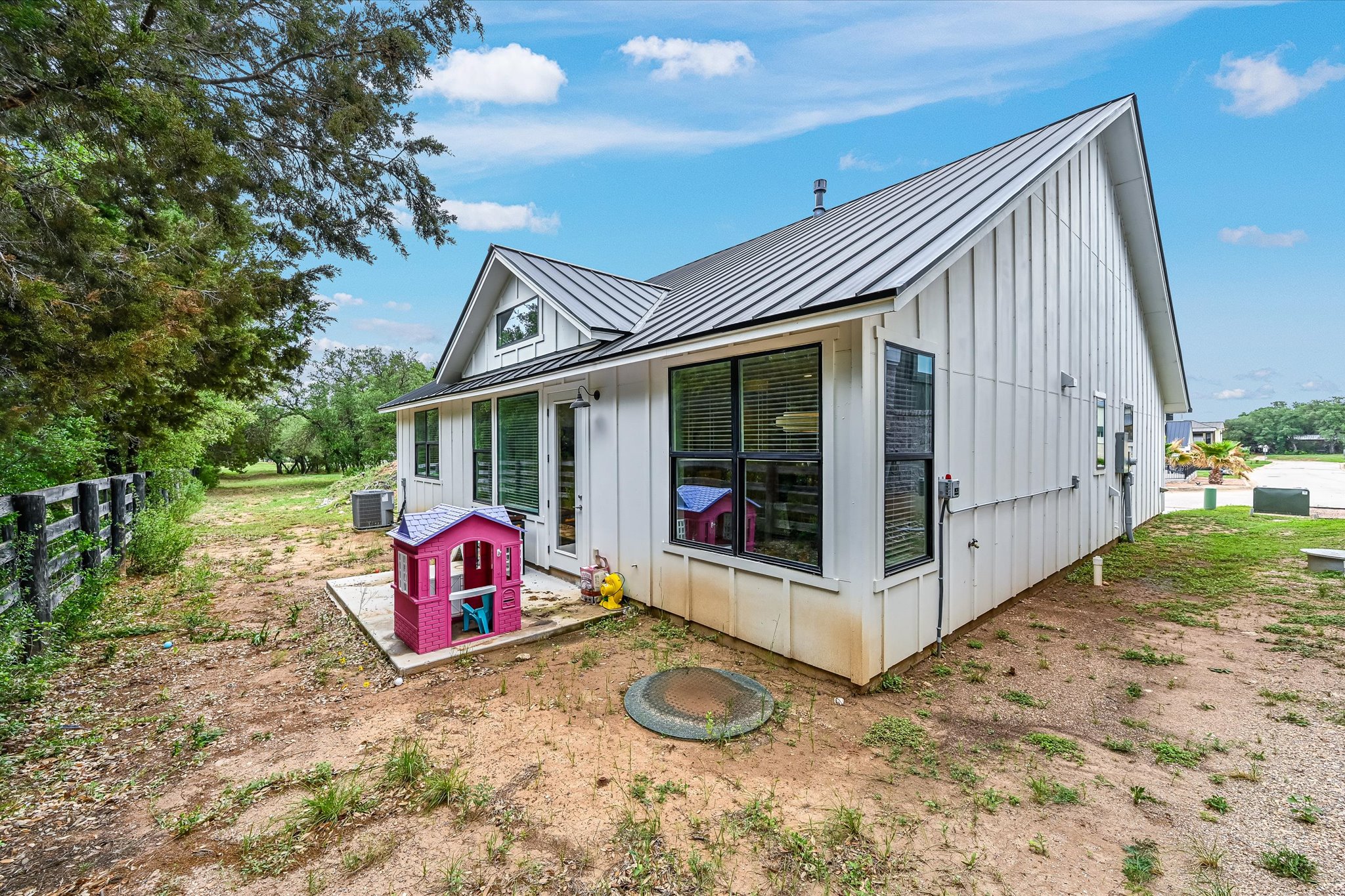 2308 Kellie Brooke Road, Unit 13 Spicewood, TX 78669 - Photo 17 of 19 The property features white vertical siding, a dark metal roof, and multiple large windows