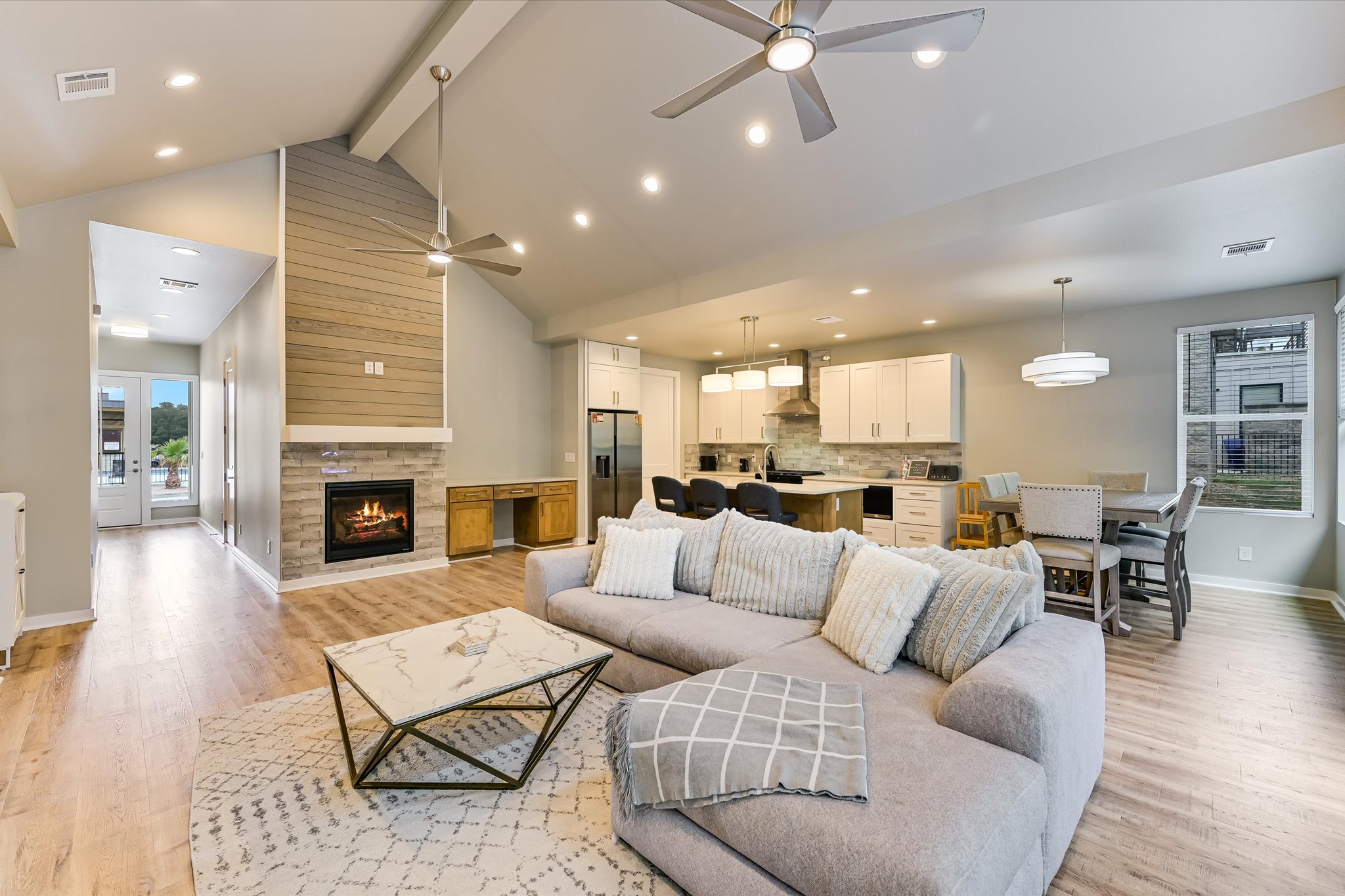 2308 Kellie Brooke Road, Unit 13 Spicewood, TX 78669 - Photo 3 of 19 The open-concept living area features a stone fireplace with a shiplap accent wall, hardwood flooring, and vaulted ceilings