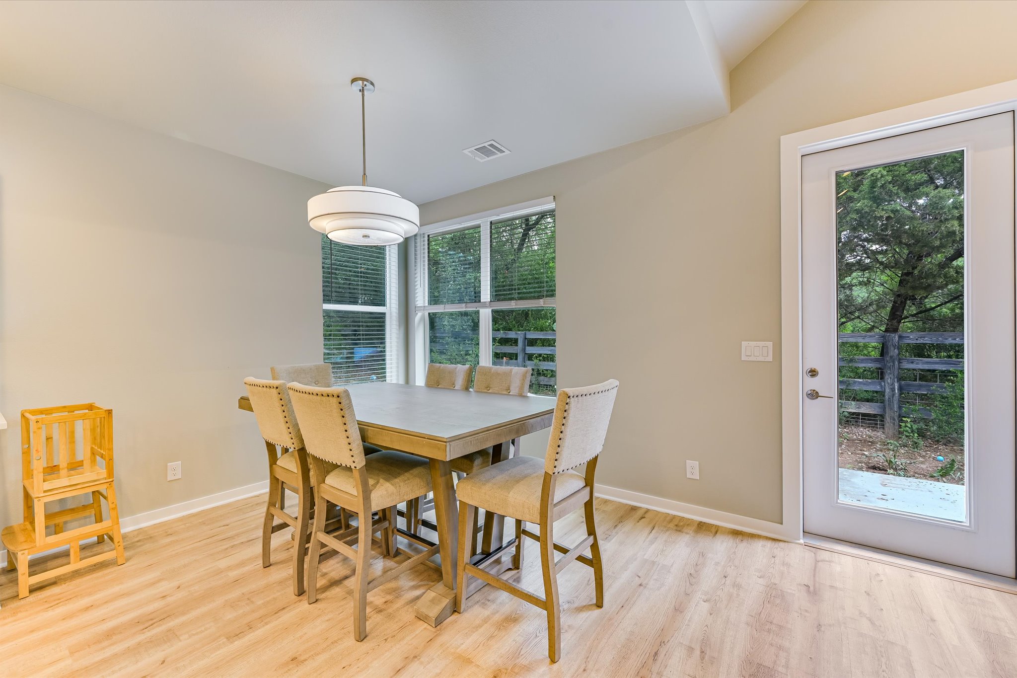 2308 Kellie Brooke Road, Unit 13 Spicewood, TX 78669 - Photo 9 of 19 Bright dining area featuring light wood flooring, a modern chandelier, and large windows with blinds