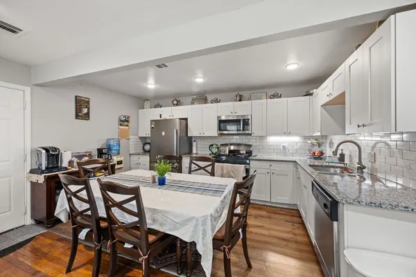 a kitchen with stainless steel appliances kitchen island granite countertop a dining table chairs and sink