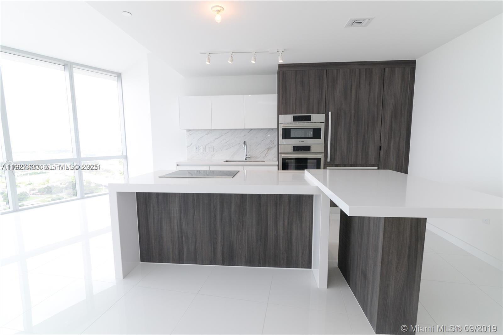 851 Northeast 1st Avenue, Unit 4110 Miami, FL 33132 - Photo 4 of 9 a kitchen with stainless steel appliances a stove a sink and a refrigerator with wooden floor