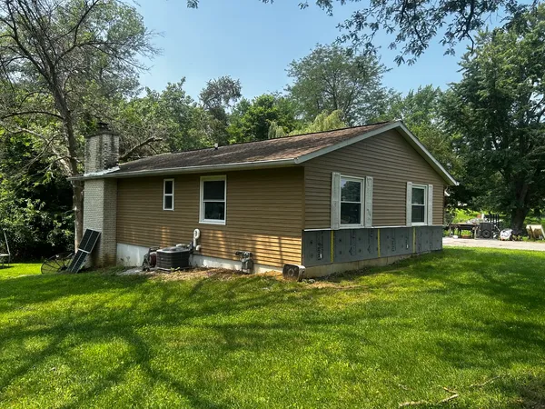 a backyard of a house with table and chairs and large trees