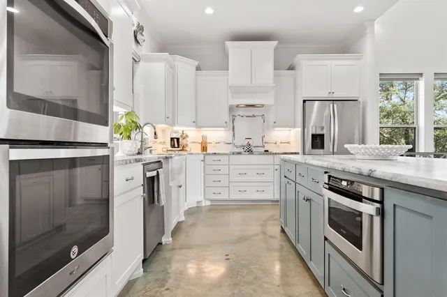 a kitchen with stainless steel appliances granite countertop a stove a sink and a refrigerator