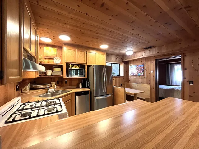 a kitchen with stainless steel appliances granite countertop a refrigerator a sink dishwasher a stove and white countertops with wooden floor