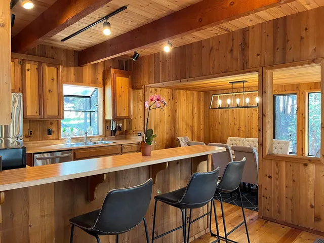a dining hall with stainless steel appliances a sink window and chairs