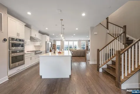 a open kitchen with kitchen island a stove a refrigerator wooden floor and a stove top oven