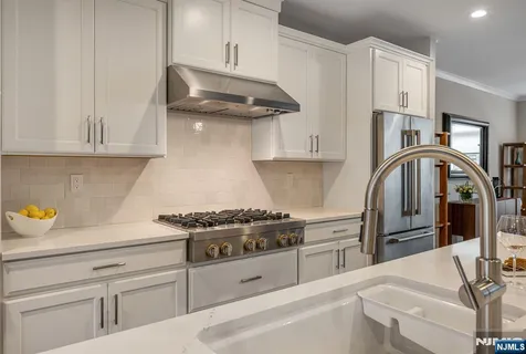 a kitchen with stainless steel appliances granite countertop a stove a refrigerator and a white cabinets