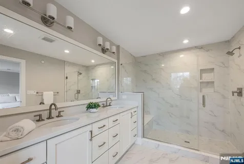 a bathroom with a granite countertop double vanity sink mirror shower and double