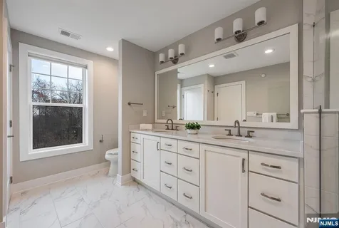 a bathroom with a granite countertop sink mirror and next to a window
