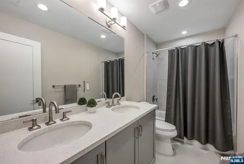 a bathroom with double vanity sink a toilet a mirror and shower curtain