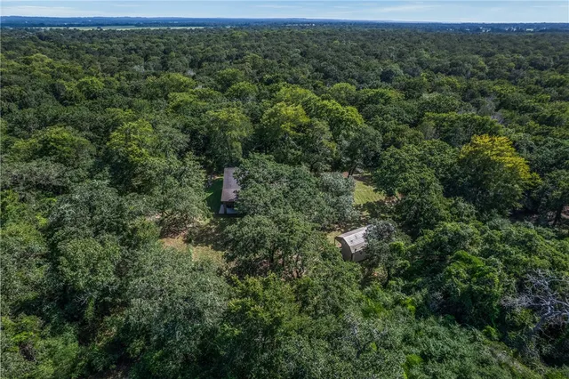 an aerial view of residential houses with outdoor space and trees