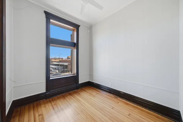 a view of an empty room with wooden floor and a window