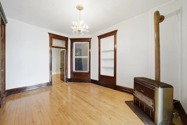 a view of an empty room with window and wooden floor
