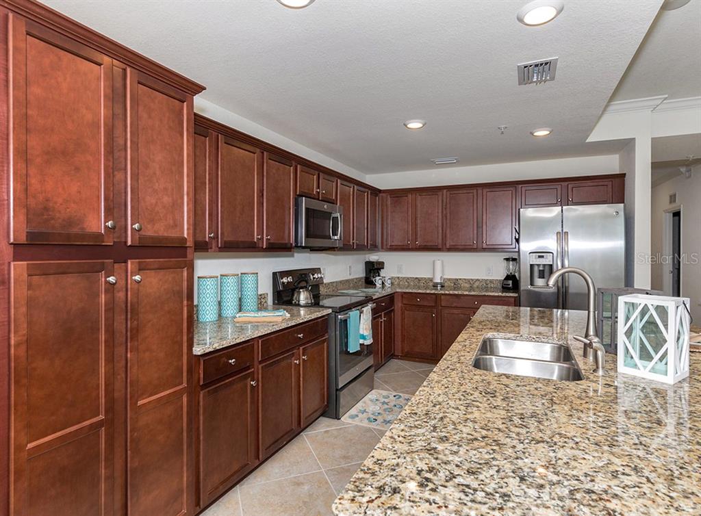 16904 Vardon Terrace, Unit 202 Lakewood Ranch, FL 34211 - Photo 16 of 30 a kitchen with stainless steel appliances granite countertop a sink refrigerator stove and microwave
