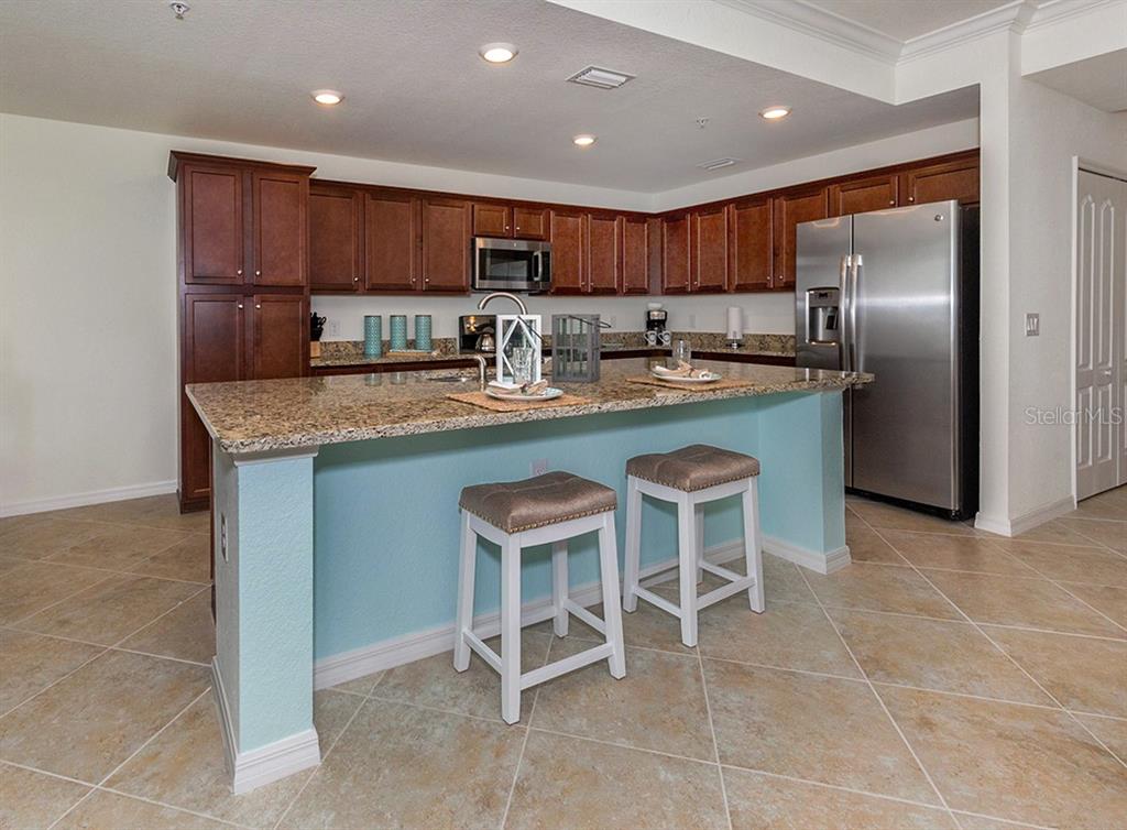 16904 Vardon Terrace, Unit 202 Lakewood Ranch, FL 34211 - Photo 17 of 30 a kitchen with stainless steel appliances granite countertop a table and chairs in it