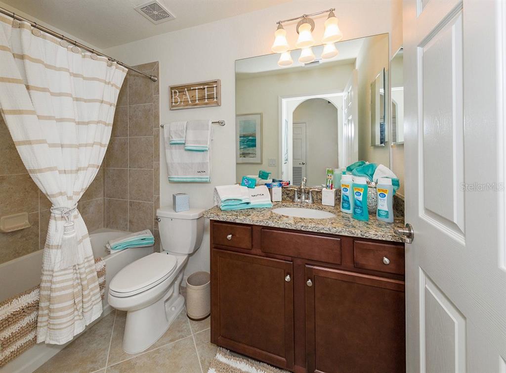 16904 Vardon Terrace, Unit 202 Lakewood Ranch, FL 34211 - Photo 24 of 30 a bathroom with a granite countertop toilet a sink and a mirror