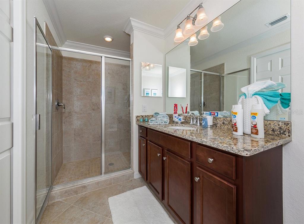16904 Vardon Terrace, Unit 202 Lakewood Ranch, FL 34211 - Photo 27 of 30 a bathroom with a granite countertop sink a shower and a mirror
