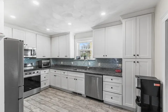 a kitchen with stainless steel appliances granite countertop a refrigerator stove and white cabinets