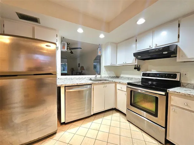 a kitchen with stainless steel appliances granite countertop a refrigerator a stove and a sink