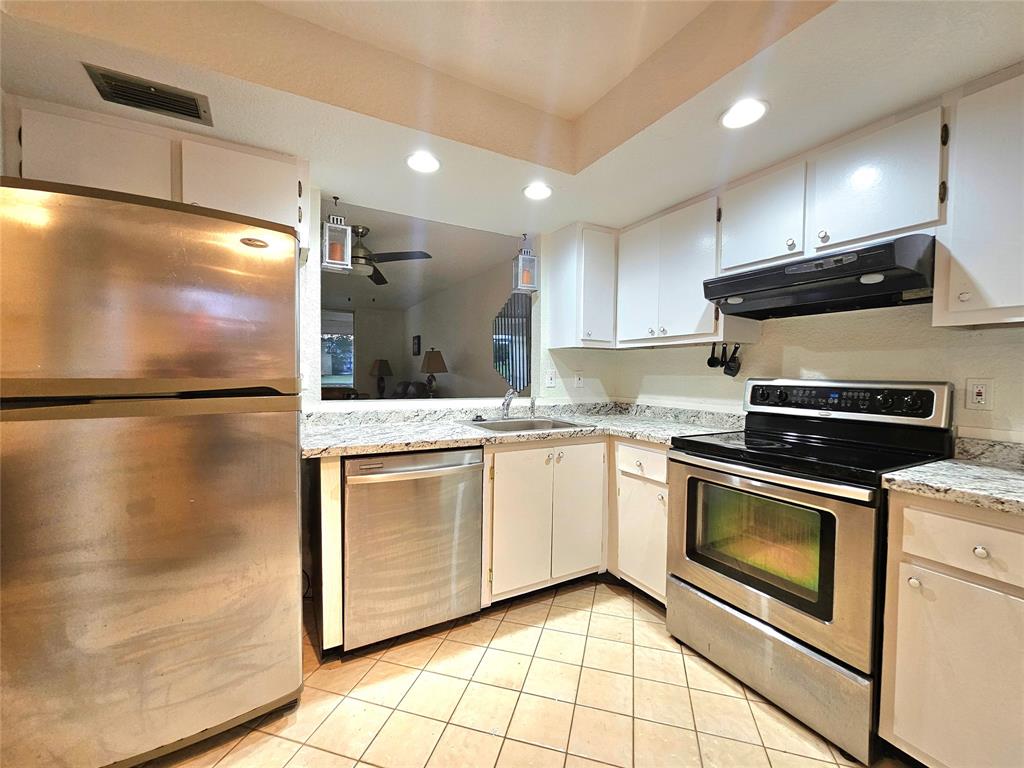 a kitchen with stainless steel appliances granite countertop a refrigerator a stove and a sink