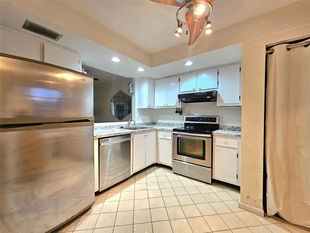 a kitchen with granite countertop a refrigerator a stove top oven a sink and dishwasher