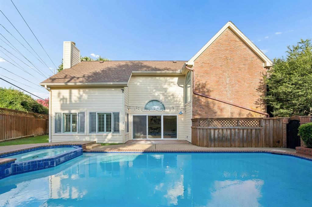 4115 Rive Lane Addison, TX 75001 - Photo 20 of 25 Exterior showcasing a private swimming pool with integrated spa, a neutral-toned siding facade, and brick accents