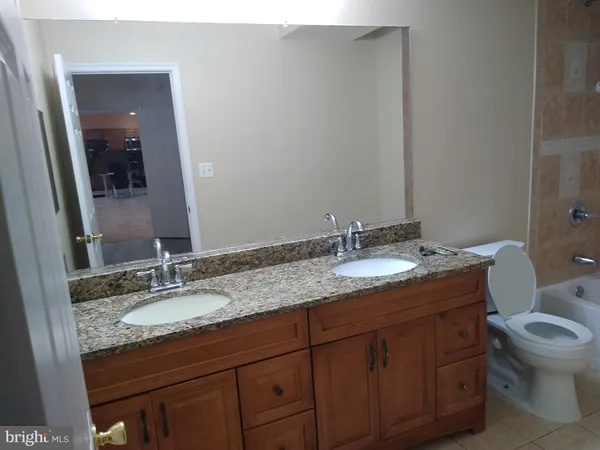 a bathroom with a granite countertop sink a toilet and mirror