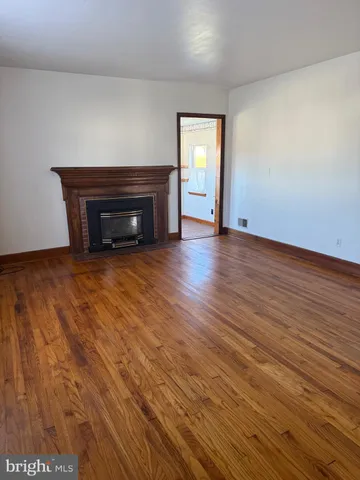 a view of empty room with wooden floor and fireplace