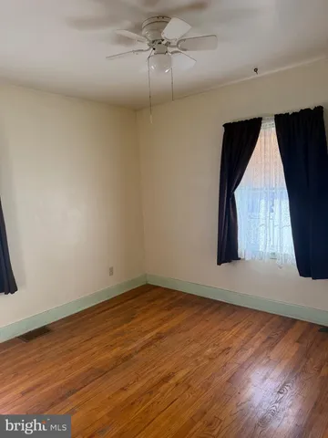 an empty room with wooden floor and fan