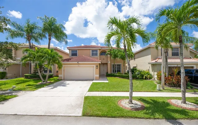 a front view of a house with a yard and palm tree
