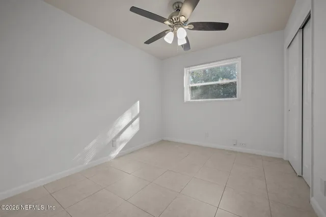 an empty room with a window and a fan