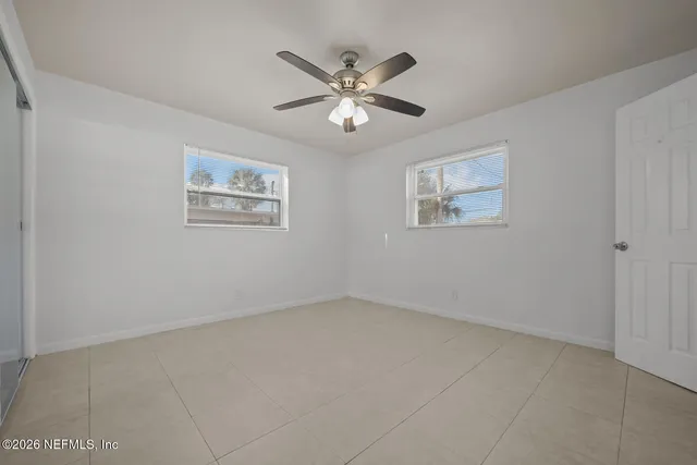 an empty room with window and ceiling fan