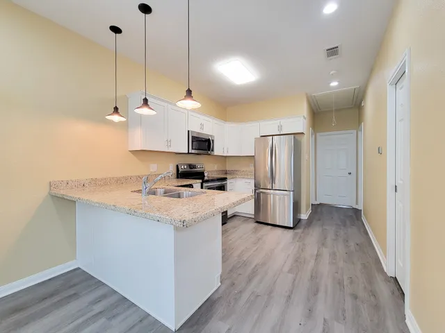 a kitchen with stainless steel appliances granite countertop a sink a stove a refrigerator and island with wooden floor