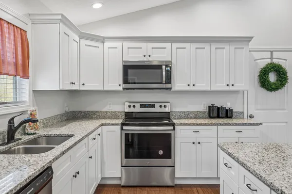 a kitchen with granite countertop white cabinets white stainless steel appliances and a sink