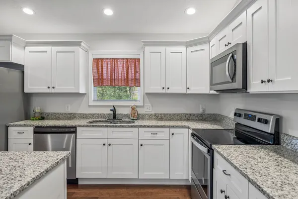 a kitchen with granite countertop cabinets stainless steel appliances and a sink