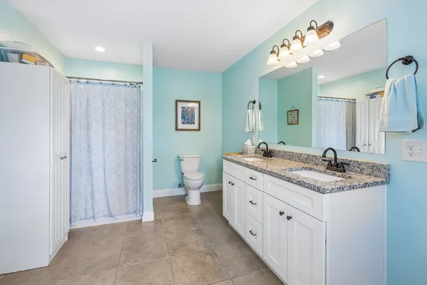 a spacious bathroom with a granite countertop sink a toilet and a mirror