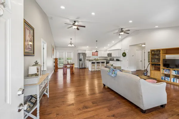 a living room with furniture kitchen view and a wooden floor
