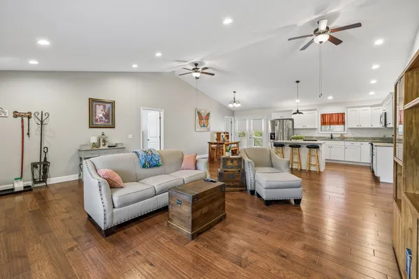 a living room with couches and kitchen view with wooden floor