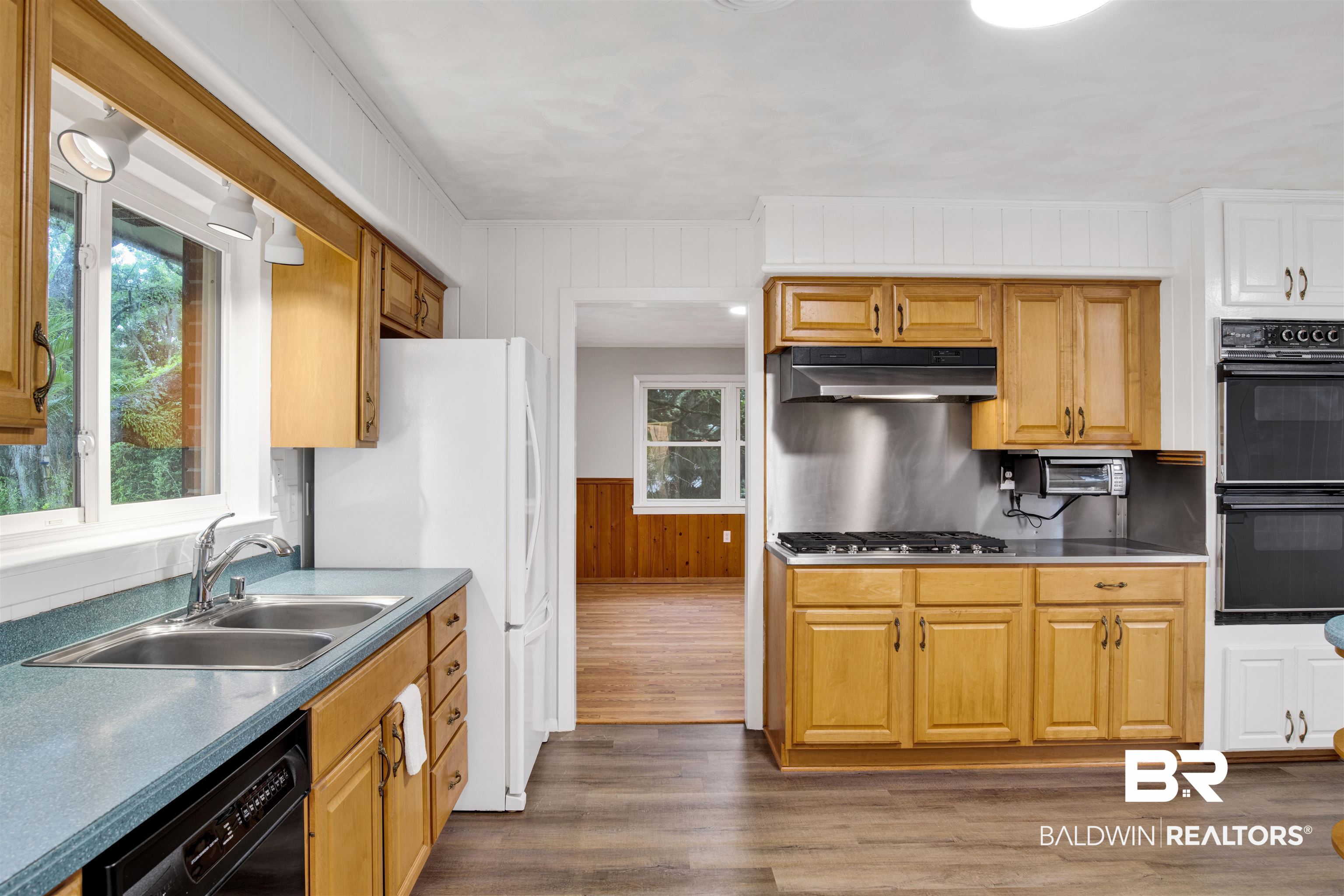 18347 Underwood Road Foley, AL 36535 - Photo 5 of 40 Kitchen with under cabinet range hood, a sink, black appliances, dark wood-style floors, and wood walls