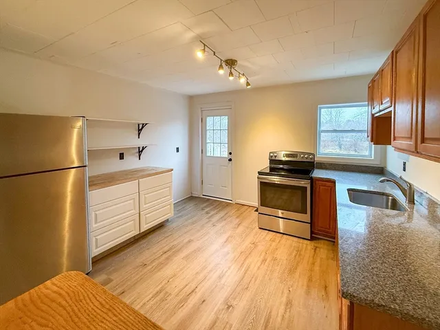 a kitchen with stainless steel appliances granite countertop a refrigerator a stove and a wooden floors