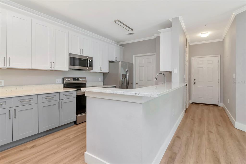 9916 Courtney Palms Boulevard, Unit 103 Tampa, FL 33619 - Photo 13 of 28 a kitchen with kitchen island white cabinets and stainless steel appliances