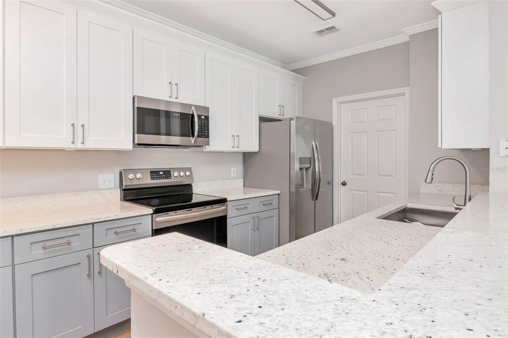 9916 Courtney Palms Boulevard, Unit 103 Tampa, FL 33619 - Photo 14 of 28 a kitchen with a refrigerator stove and white cabinets