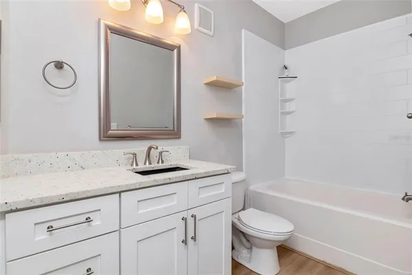 a bathroom with a granite countertop toilet sink and mirror