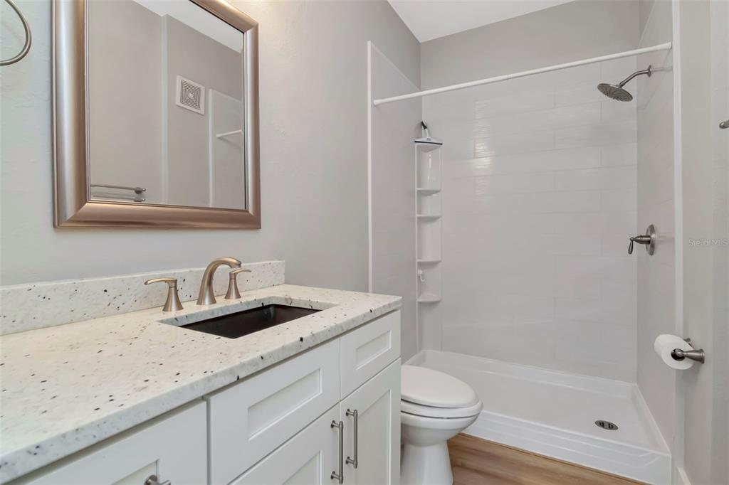 9916 Courtney Palms Boulevard, Unit 103 Tampa, FL 33619 - Photo 19 of 28 a bathroom with a granite countertop sink toilet and shower