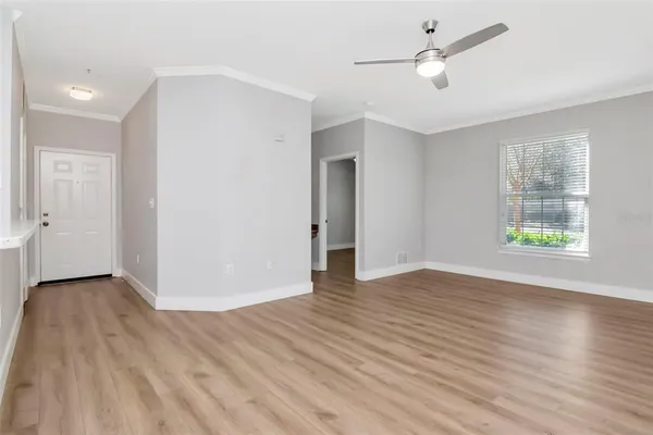 a view of an empty room with wooden floor and a window